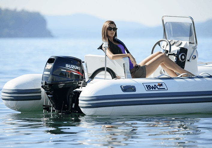 A woman sitting on the back of a boat in water.