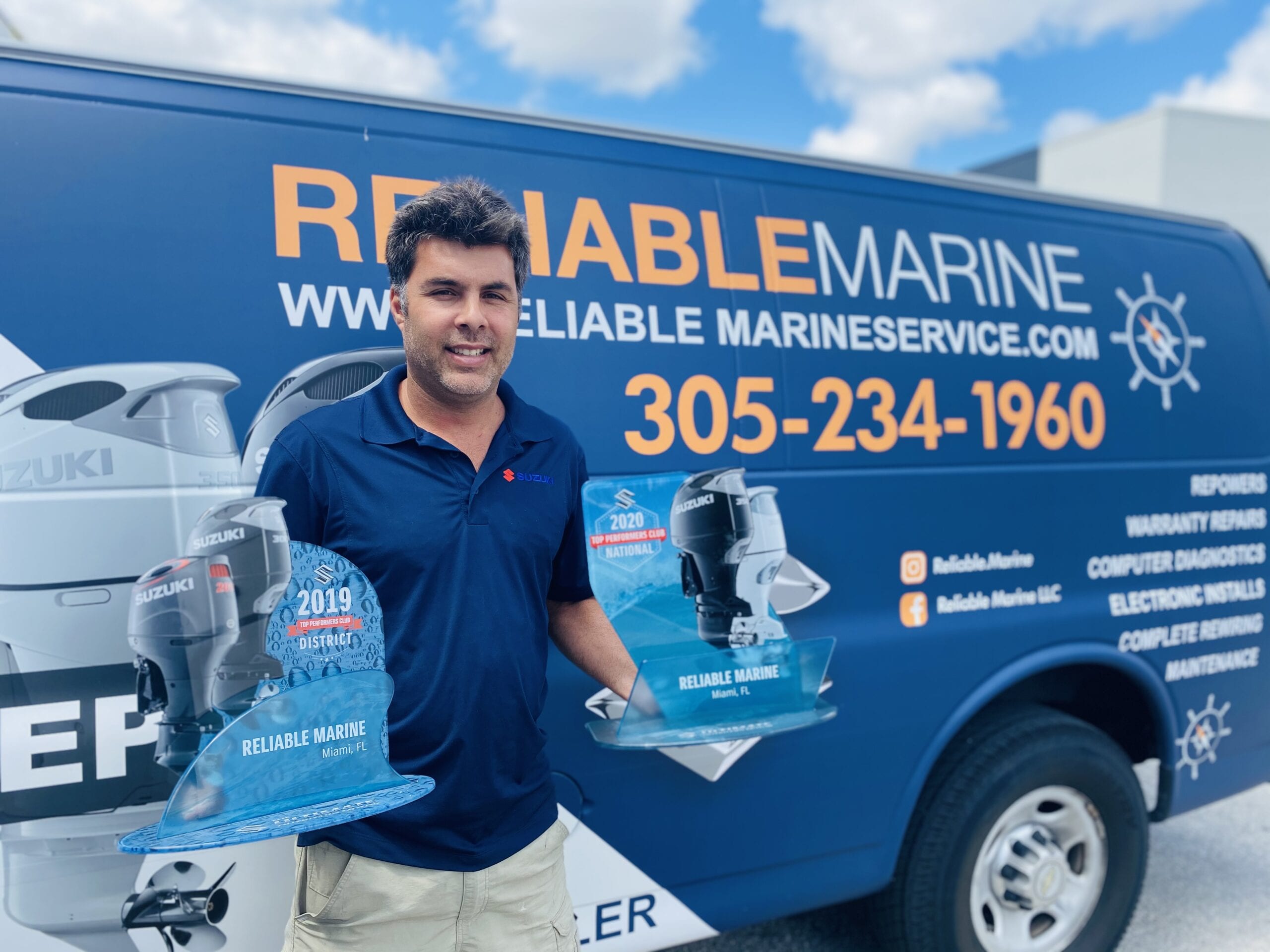 A man standing in front of a blue and white truck.